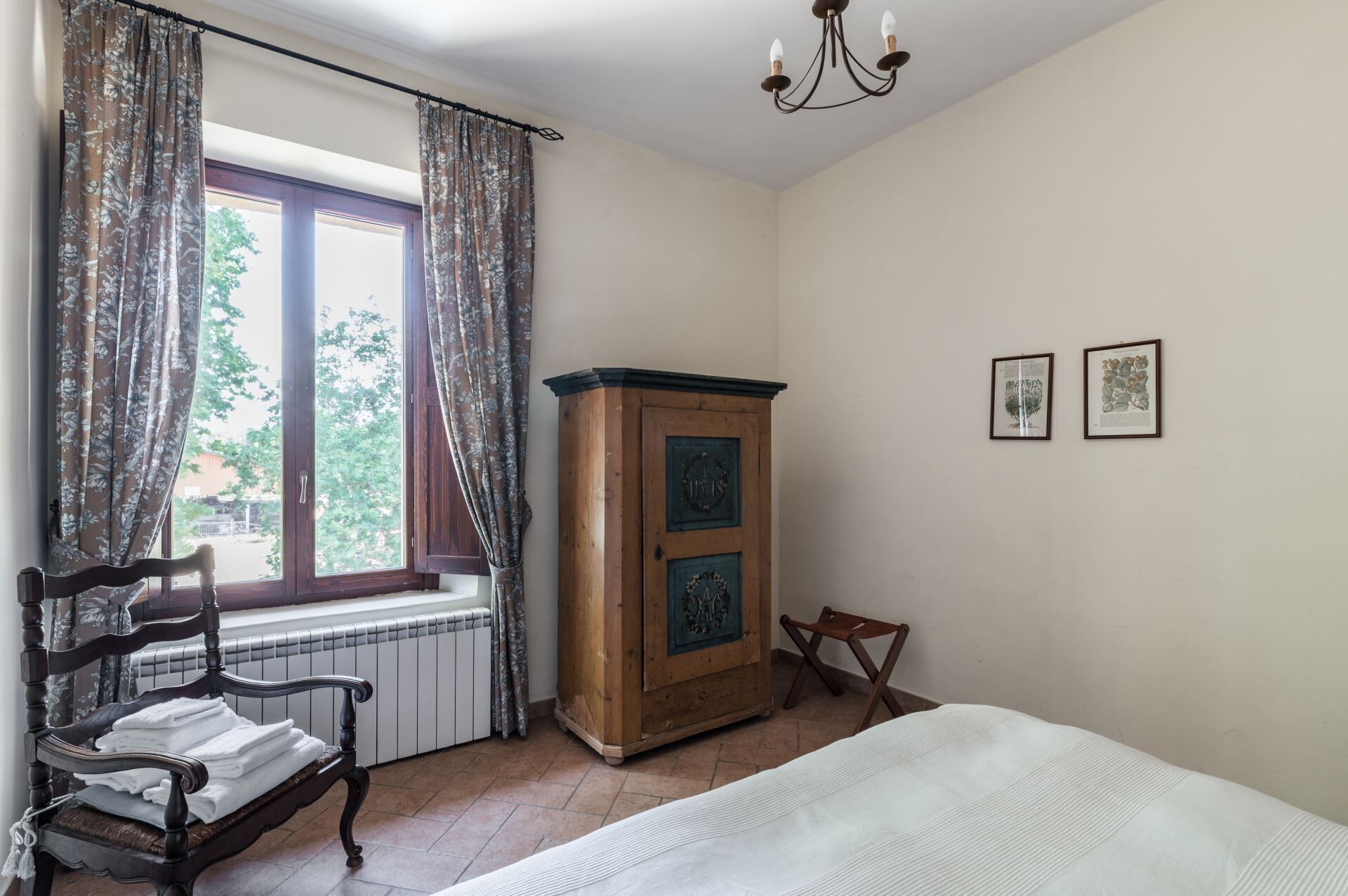 Een slaapkamer met een bed, een houten kast, een stoel en een raam met gordijnen.