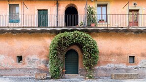 A building with a green door, an arched entrance, and a balcony with potted plants.