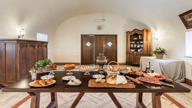 A dining table set with various foods and drinks, flanked by wooden cabinets and a bookshelf.