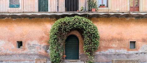 Un edificio con puerta verde, entrada en arco y balcón con macetas.