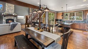 Een moderne keuken met een stenen open haard, een houten eethoek en een groot kookeiland met barstoelen.