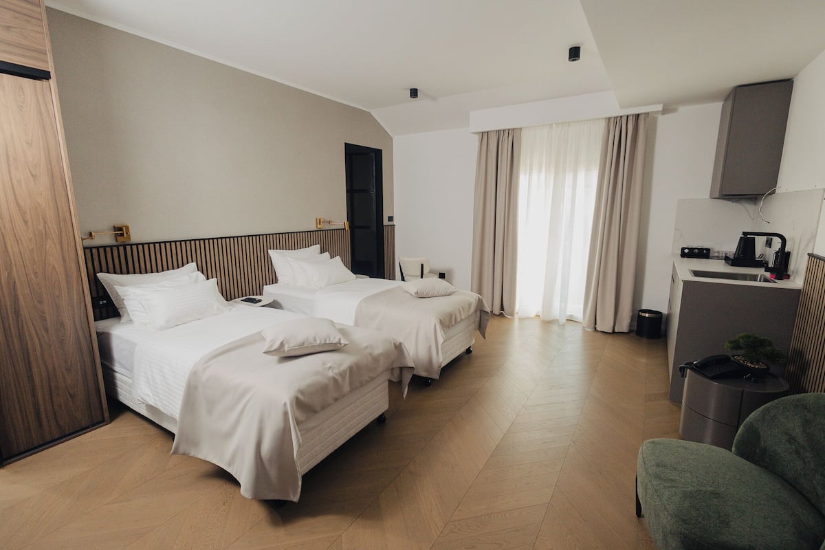 Une chambre d’hôtel avec deux lits, un bureau, une chaise et une petite poubelle.
