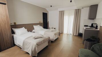 A hotel room with two beds, a desk, a chair, and a small trash bin.