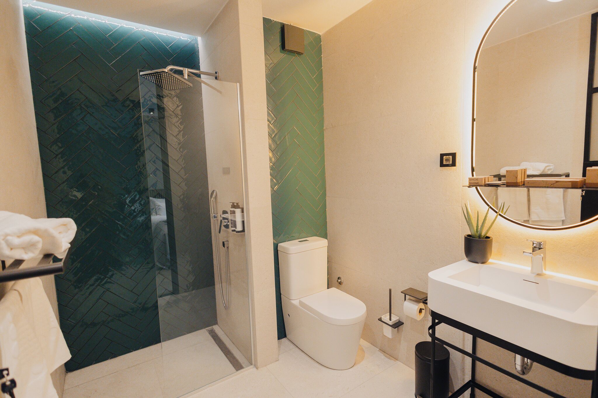 Un baño moderno con ducha de vidrio, inodoro blanco y lavamanos con espejo.