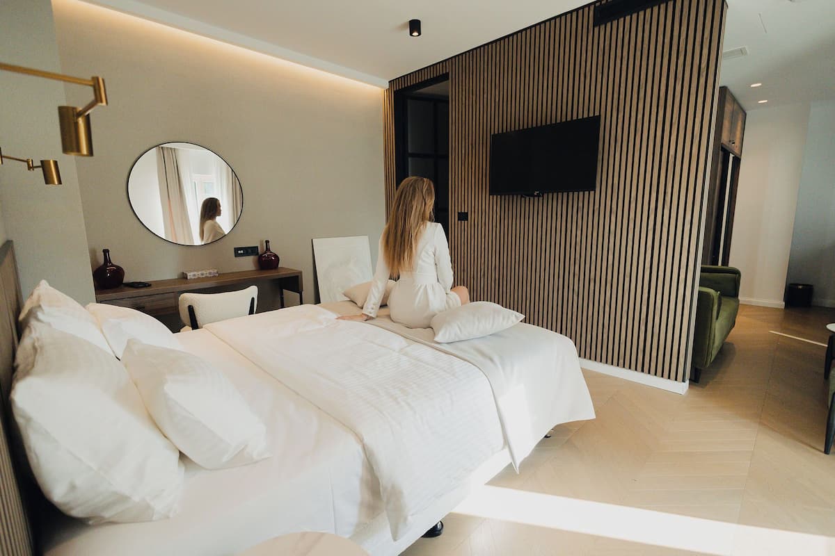 Une chambre d’hôtel moderne avec un grand lit, un bureau et un téléviseur fixé au mur.