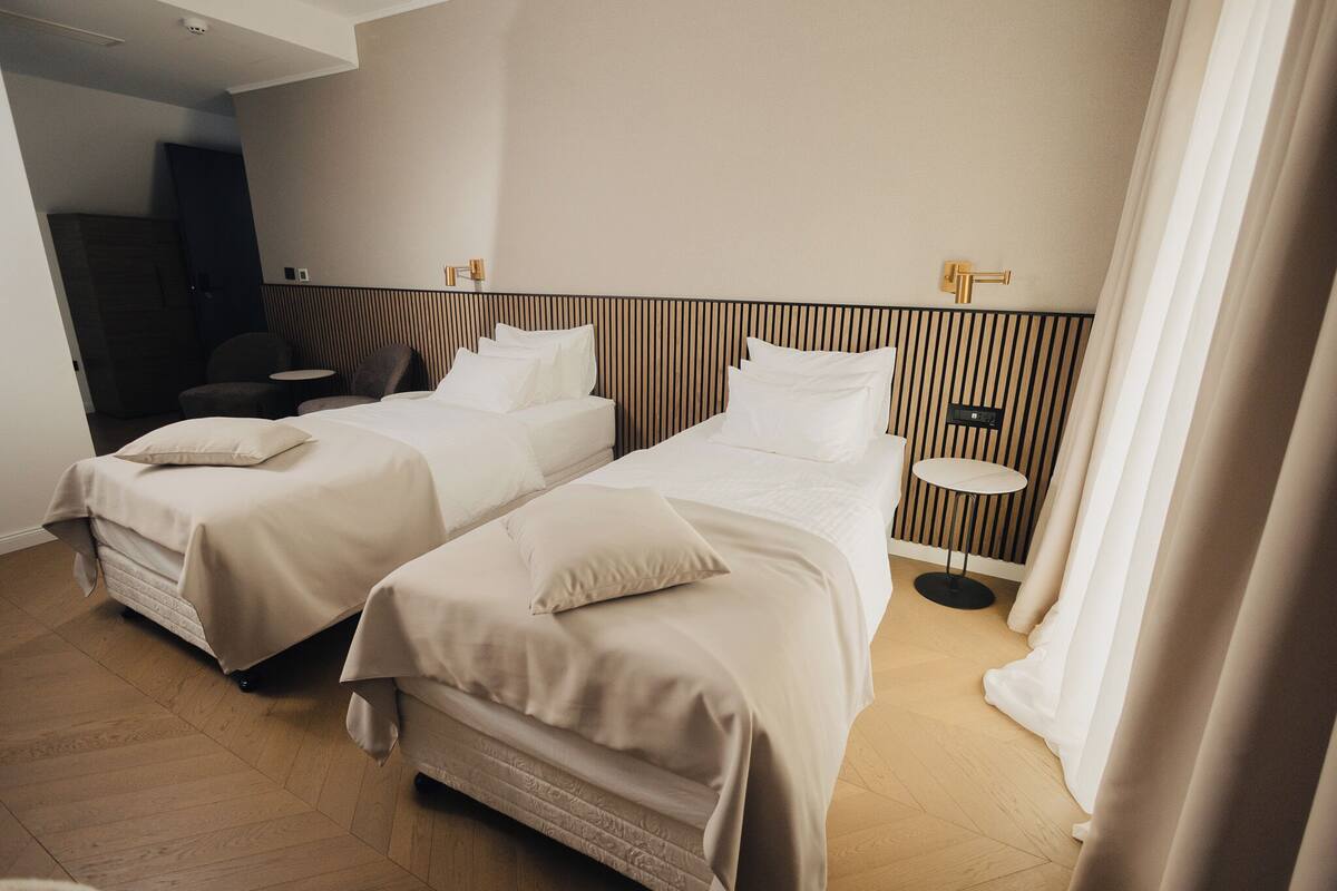 Une chambre d’hôtel avec deux lits, une petite table ronde et une armoire.