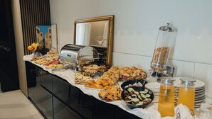 A buffet with various food items and a juice dispenser. - Hotel Flaneur (Belgrade)
