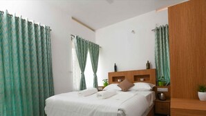 A neatly arranged bedroom with a bed, bedside tables, and curtains. - Rains Valley Resort By Teal Luxury Stays (Devikolam)