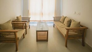 A room with two wooden sofas and a central table, with a window and curtains in the background. - Rains Valley Resort By Teal Luxury Stays (Devikolam)