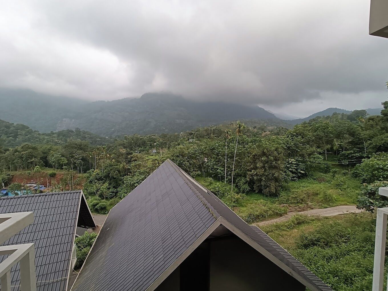 A view of a mountainous landscape with dense greenery and a cloudy sky.