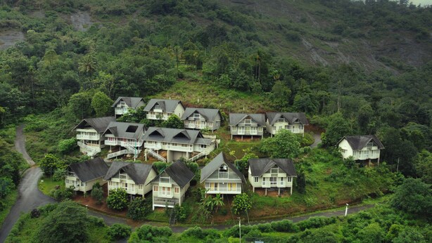 A cluster of houses with multiple stories and balconies, surrounded by dense greenery and hills. - Rains Valley Resort By Teal Luxury Stays (Devikolam)