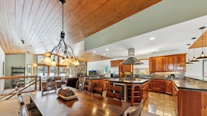 A spacious kitchen with wooden cabinets, a large island, and pendant lighting.