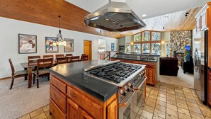 A spacious kitchen with a central island, wooden cabinetry, and a stone accent wall.