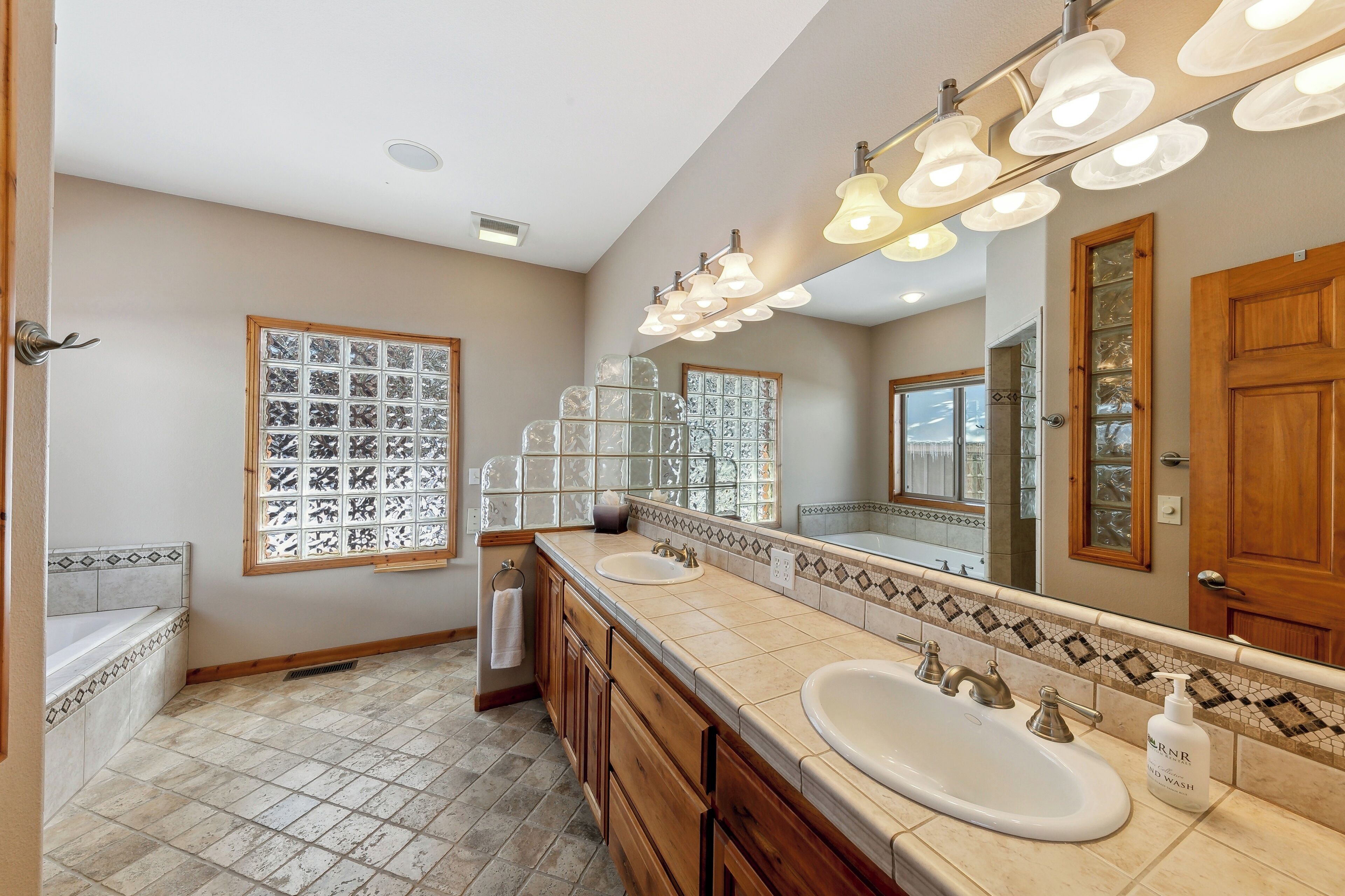 Un baño con dos lavamanos, un espejo grande y azulejos decorativos.
