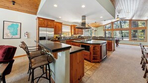 A spacious kitchen with wooden cabinets, a large island, and a view through the windows.