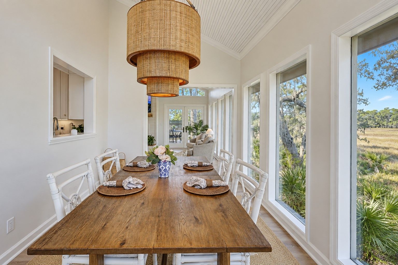 Une salle à manger avec une table en bois, des chaises blanches et un luminaire suspendu.