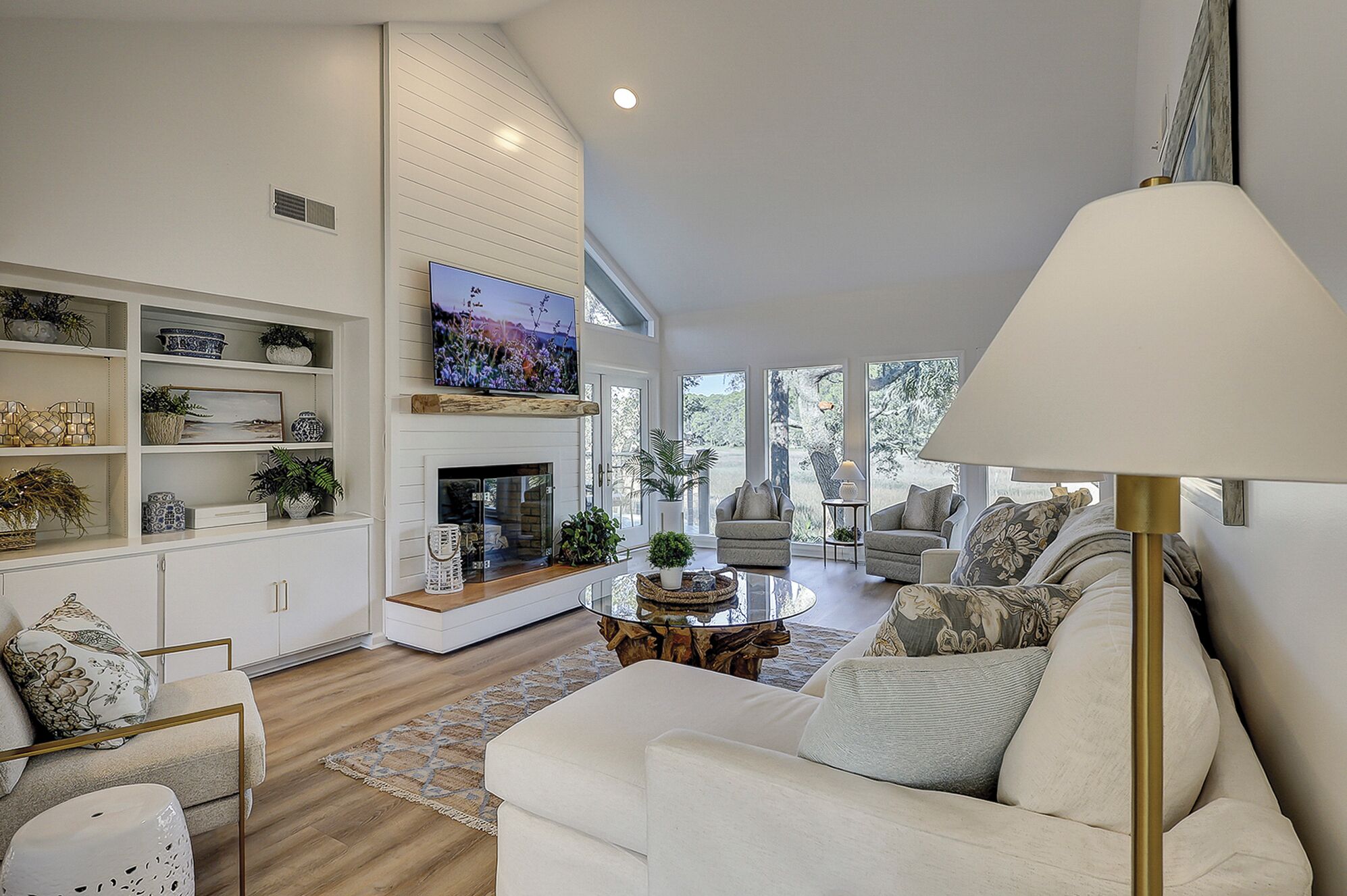 A spacious living room with a fireplace, comfortable seating, and a television mounted on the wall.