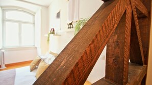 Een houten trap in een kamer met een groot raam, een bed en een plant.