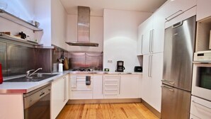 Een moderne keuken met roestvrijstalen apparatuur, witte kasten en een houten vloer.