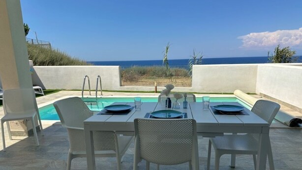 Zona pranzo all'aperto con piscina e vista sull'oceano.
