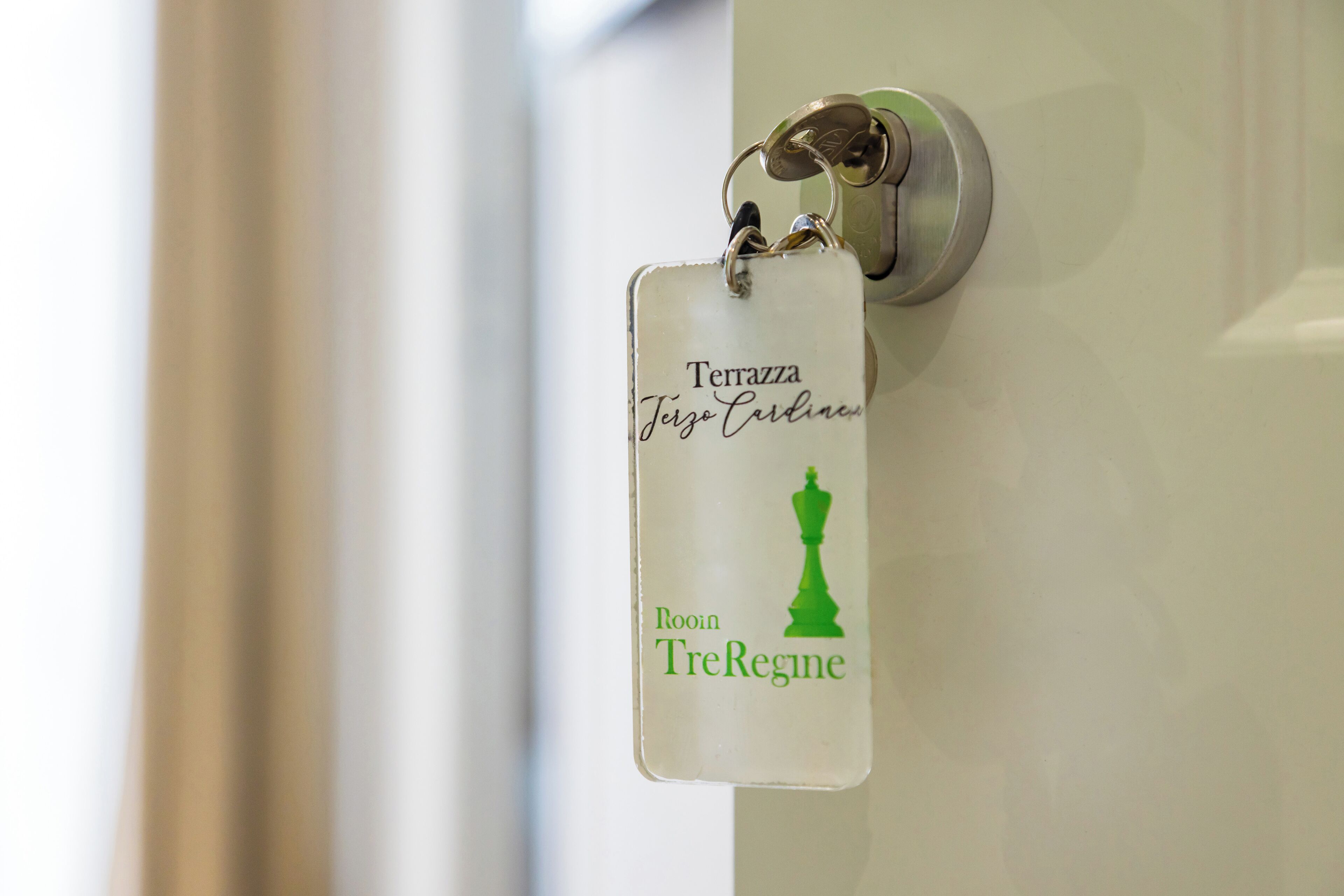 A keycard with "Terrazza Terzo Cardino" and "Rooin TreRegine" text, attached to a door handle.
