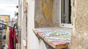 A narrow street with a building featuring a colorful tiled balcony. - Terrazza Terzo Cardine (Naples)
