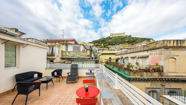 A rooftop terrace with outdoor seating, a view of a historic hilltop building, and a white railing. - Terrazza Terzo Cardine (Naples)