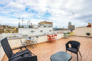 Une terrasse sur le toit avec des sièges en plein air, une vue sur le paysage urbain et un bâtiment doté d’antennes.