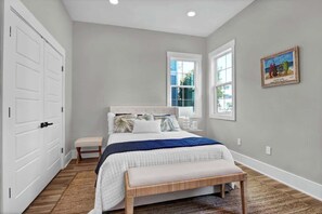 Un dormitorio con cama, un banco, una ventana y una puerta.