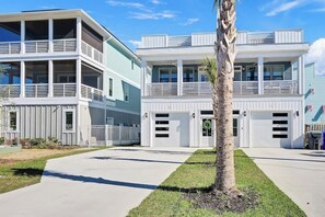A two-story residential building with a balcony, a garage, and a well-maintained lawn. - Shenanigans on the Sea (SOS) (Carolina Beach)