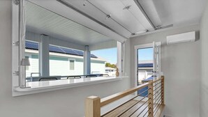 Un intérieur moderne avec un escalier en bois, un balcon offrant une vue sur un immeuble doté de panneaux solaires et un plafond blanc.