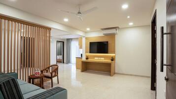 A modern living room with a sofa, a wooden partition, a TV mounted on the wall, and a ceiling fan.