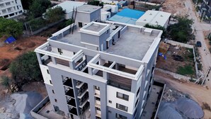 A multi-story building with a flat roof, large windows, and a central courtyard.