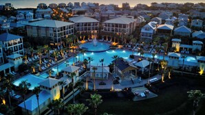 A resort with a central pool, multiple buildings, and a view of the ocean at sunset. - Tranquil Shores | Walk to Beach | Largest 30A Pool | Sleeps 12 | 6 Bikes (Panama City Beach)