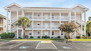 A multi-story hotel with a symmetrical facade, balconies, and a parking lot with handicapped spaces.