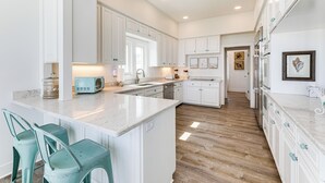 Una cocina amplia con armarios blancos, una isla central y piso de madera.