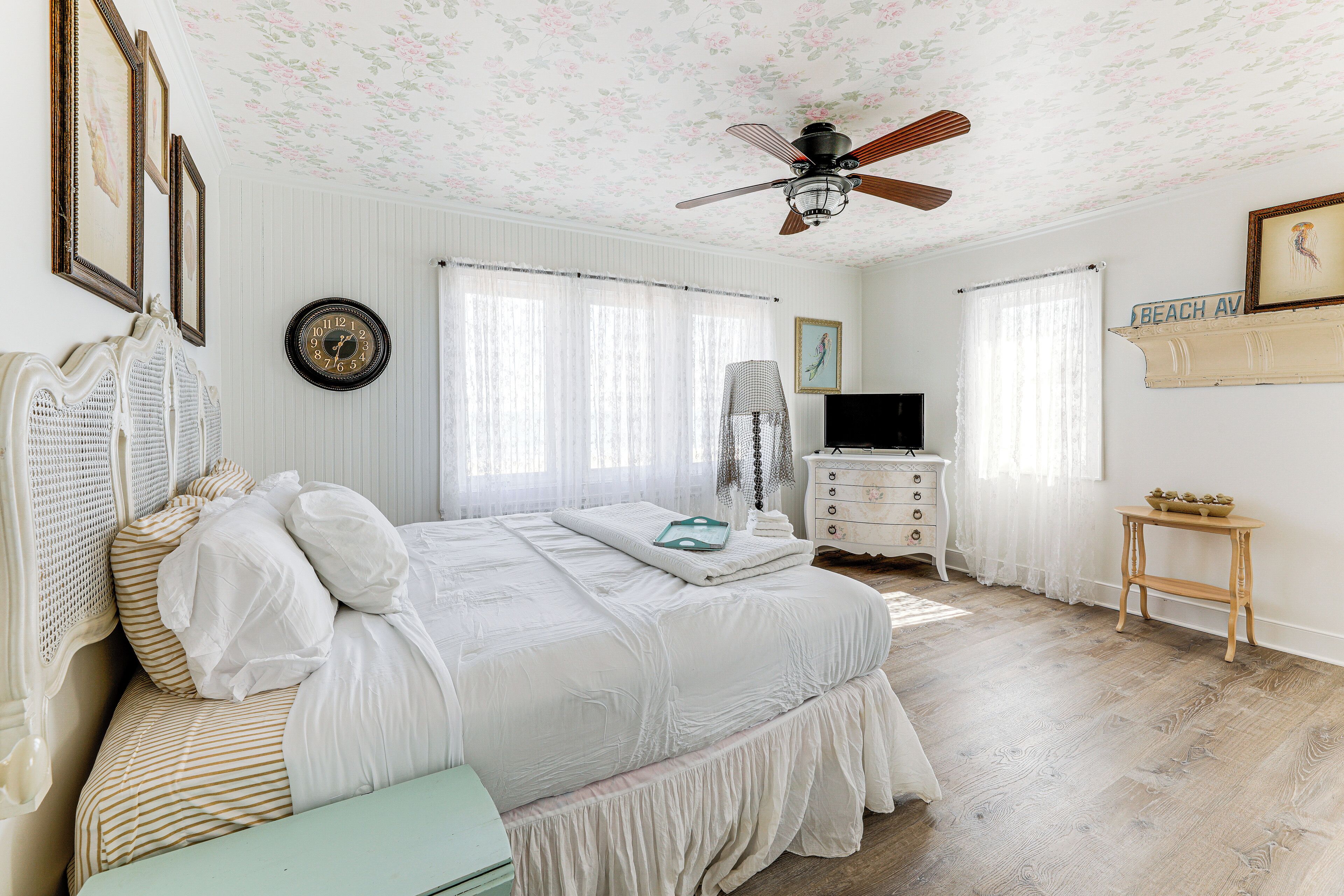 A bedroom with a bed, a dresser, a television, and a ceiling fan.