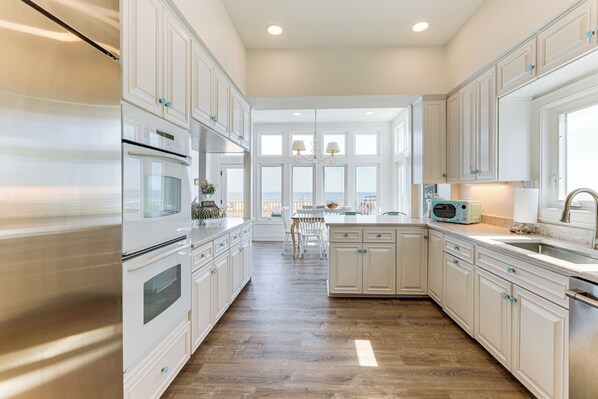 A kitchen with white cabinets, a stainless steel refrigerator, and a view to the outside. - Steps to Shore: Spacious Bethany Beach Retreat (Bethany Beach)