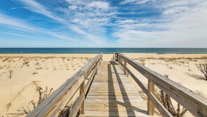 Un paseo marítimo de madera que conduce a una playa con cielos despejados.