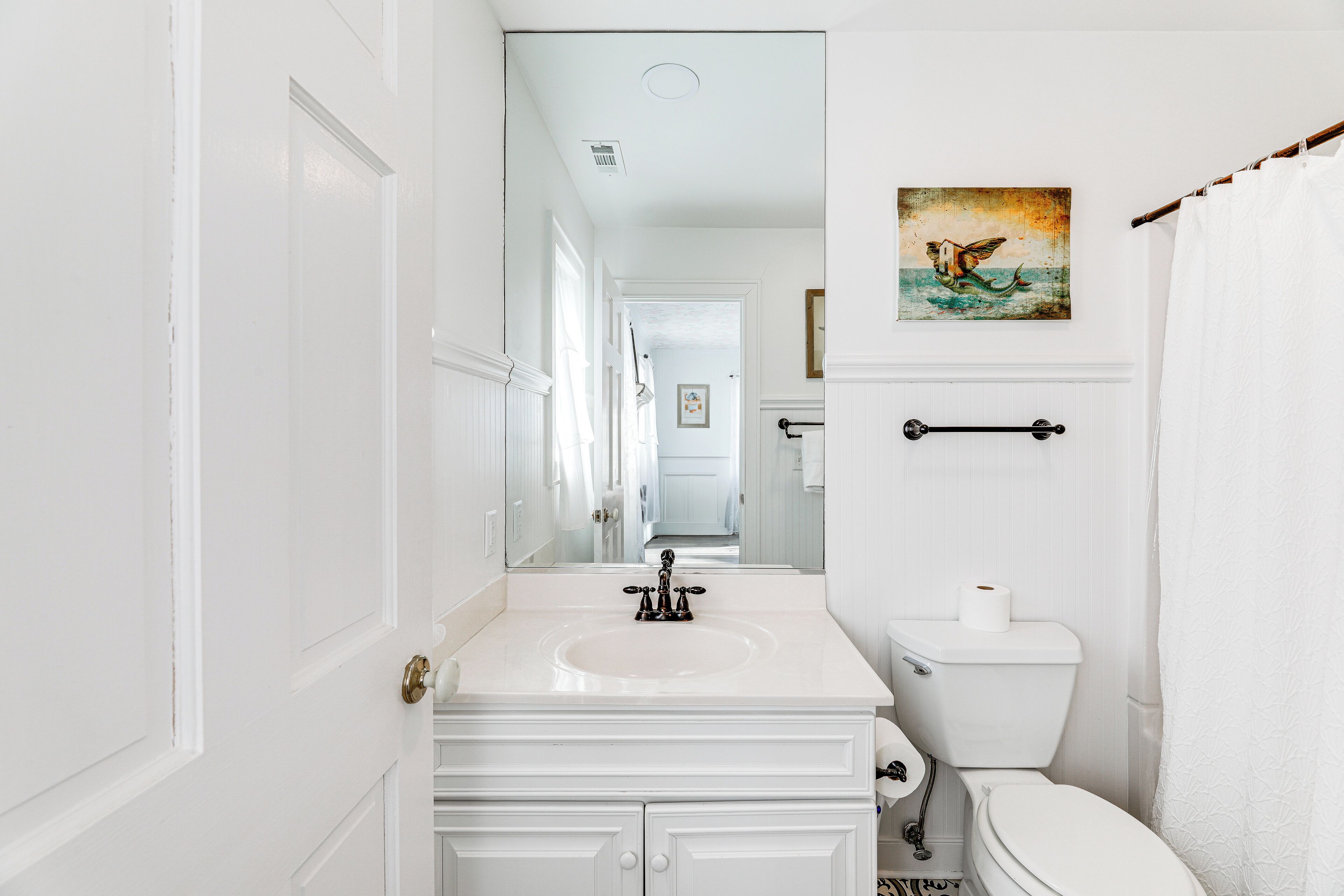 A bathroom with a white vanity, a toilet, and a towel rack.