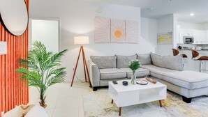 A modern living room with a grey sectional sofa, a white coffee table, and a large mirror.