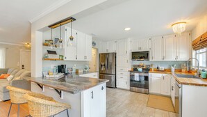 A modern kitchen with white cabinets, stainless steel appliances, and a central island with bar stools.