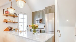 A modern kitchen with a large island, stainless steel appliances, and wooden shelves. - Luxe Designer Flat on Sloans Lake w/ Rooftop Deck (Denver)