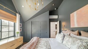 A bedroom with a large bed, a wooden dresser, a window with blinds, and a ceiling light fixture. - Luxe Designer Flat on Sloans Lake w/ Rooftop Deck (Denver)