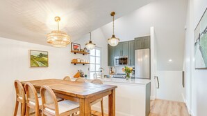 A modern kitchen with wooden dining table and chairs, stainless steel appliances, and pendant lighting. - Luxe Designer Flat on Sloans Lake w/ Rooftop Deck (Denver)