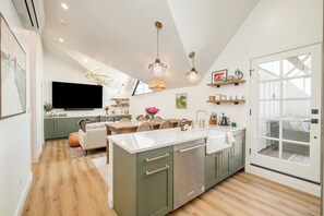 A modern kitchen with a central island, built-in appliances, and pendant lighting. - Luxe Designer Flat on Sloans Lake w/ Rooftop Deck (Denver)