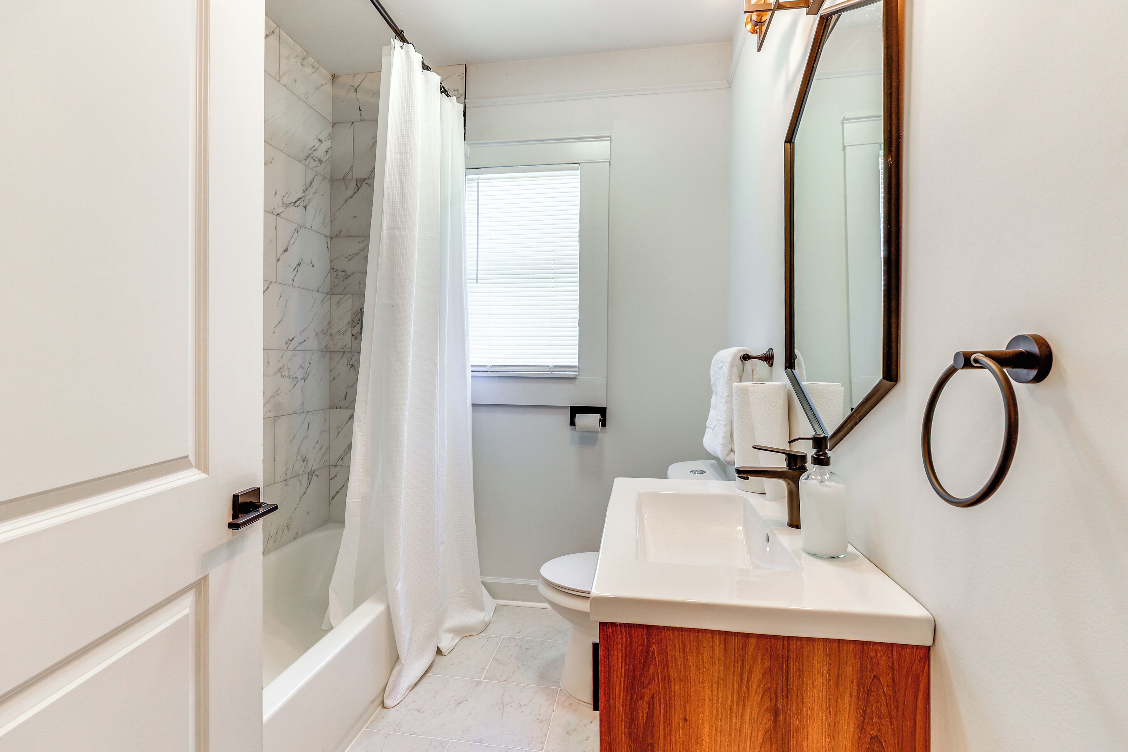 Ein Badezimmer mit Dusche, Toilette, Waschbecken und Spiegel.