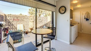 Une pièce avec une table ronde, deux chaises, un lave-linge et une horloge au mur.