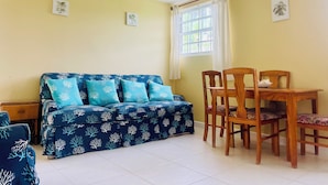 A room with a blue sofa, wooden dining table, and chairs.