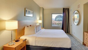 A hotel room with a large bed, a nightstand with a lamp, a dresser, and a window with curtains. - Sphere View, Near Dining & Nightlife: Luxe Condo (Las Vegas)